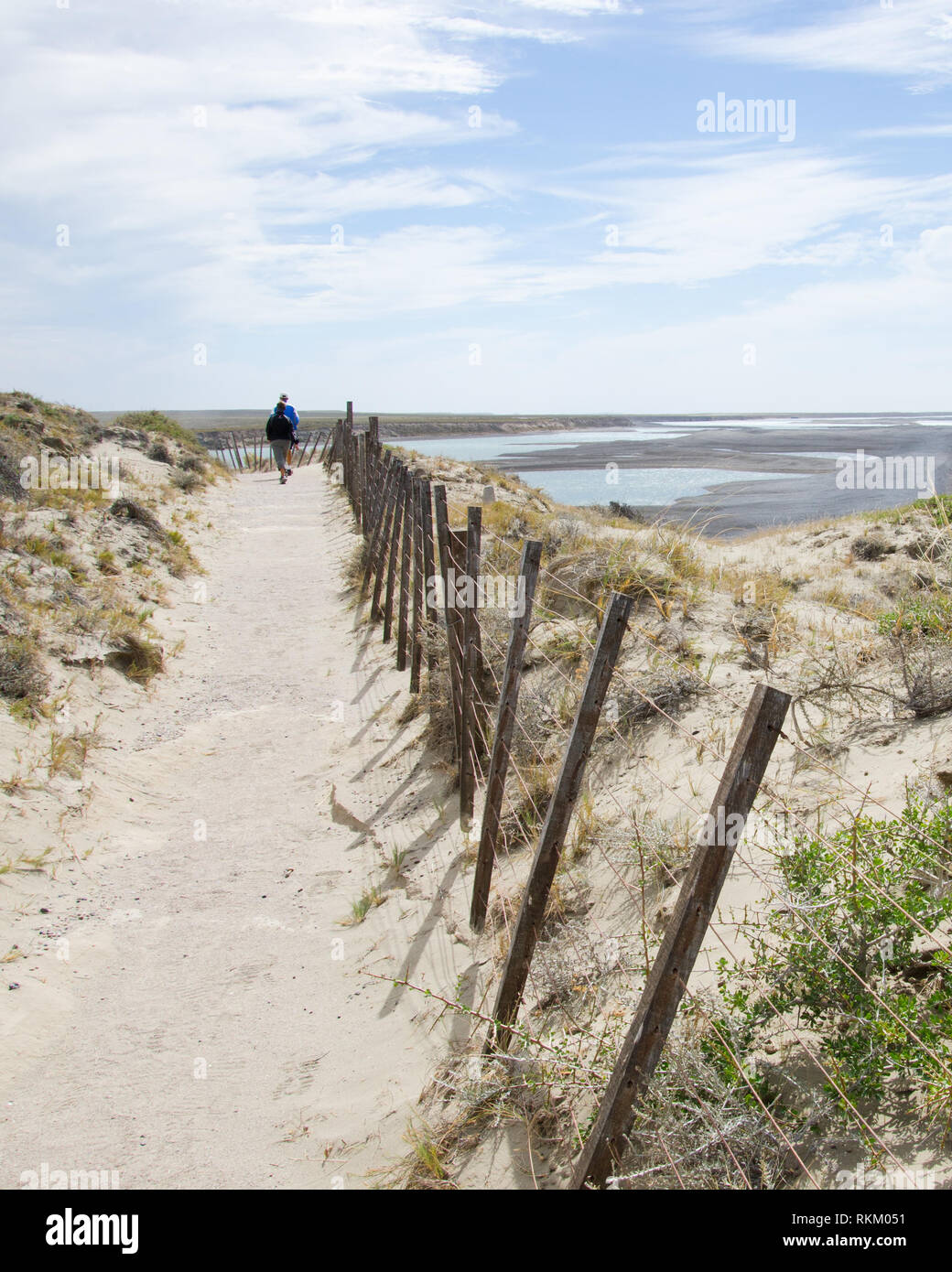 Walkers explore the barren rough coast line of Peninsula Valdes, Argentina, follow trail and fence line to view scenic Caleta Valdes. Stock Photo
