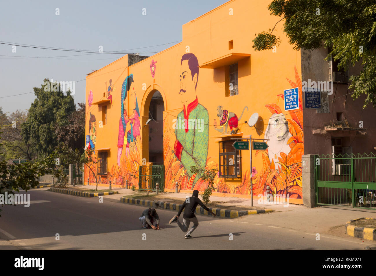 Young men creating photos in front of a wall mural painted by Mexican artist Saner in Lodhi colony, New Delhi, India Stock Photo