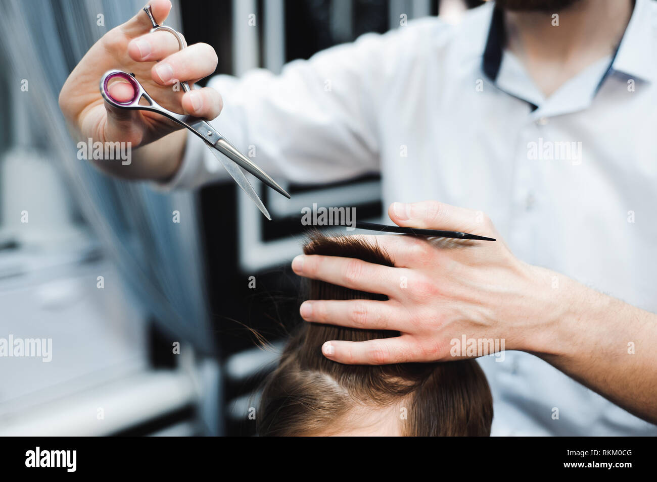 Cute little boy is getting haircut by hairdresser Stock Photo