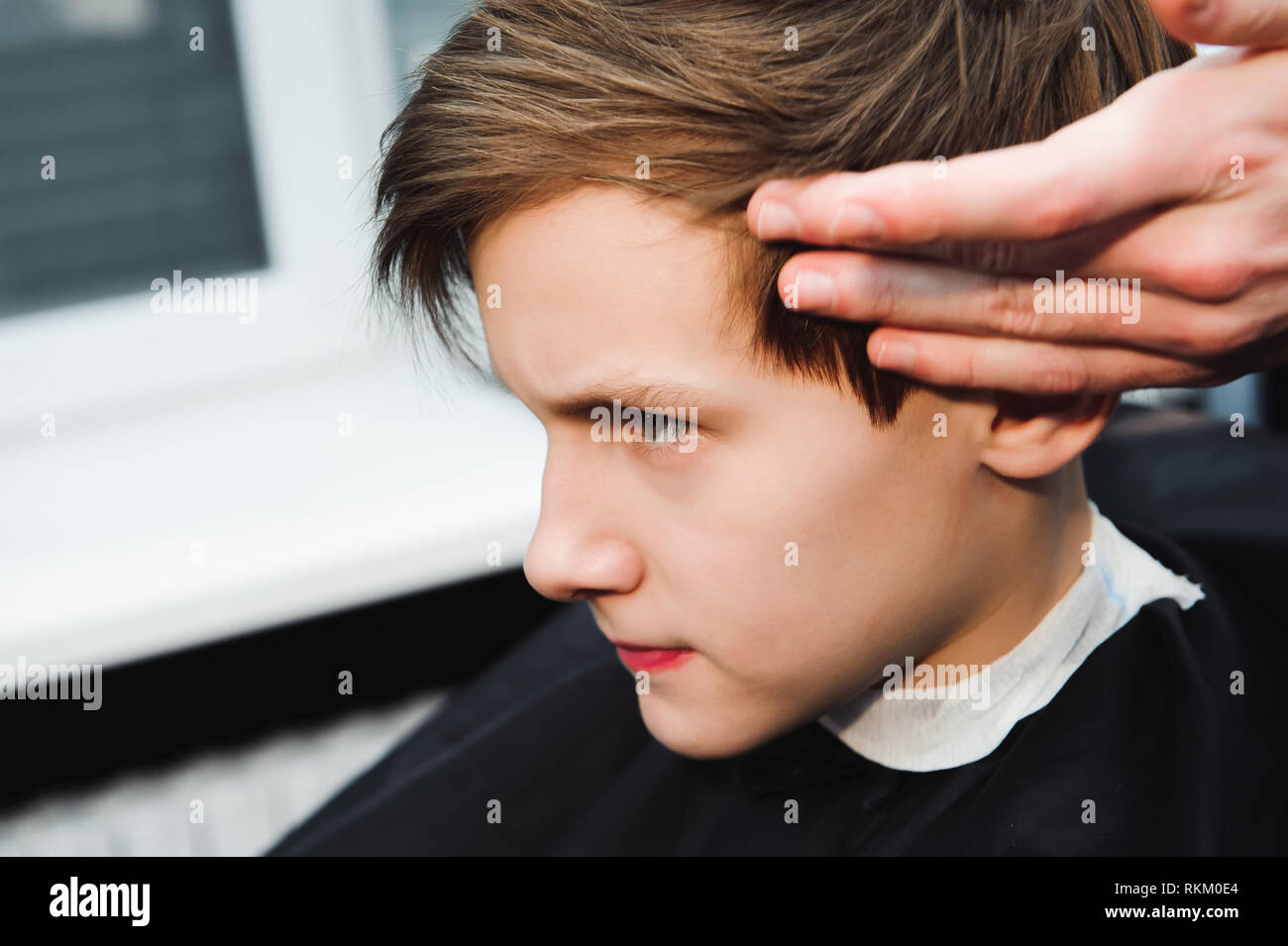 Young Handsome Barber Making Haircut Of Cute Boy In