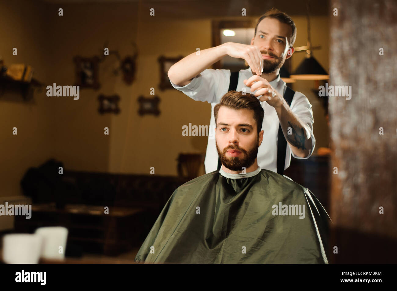 Master cuts hair and beard of men in the barbershop Stock Photo - Alamy