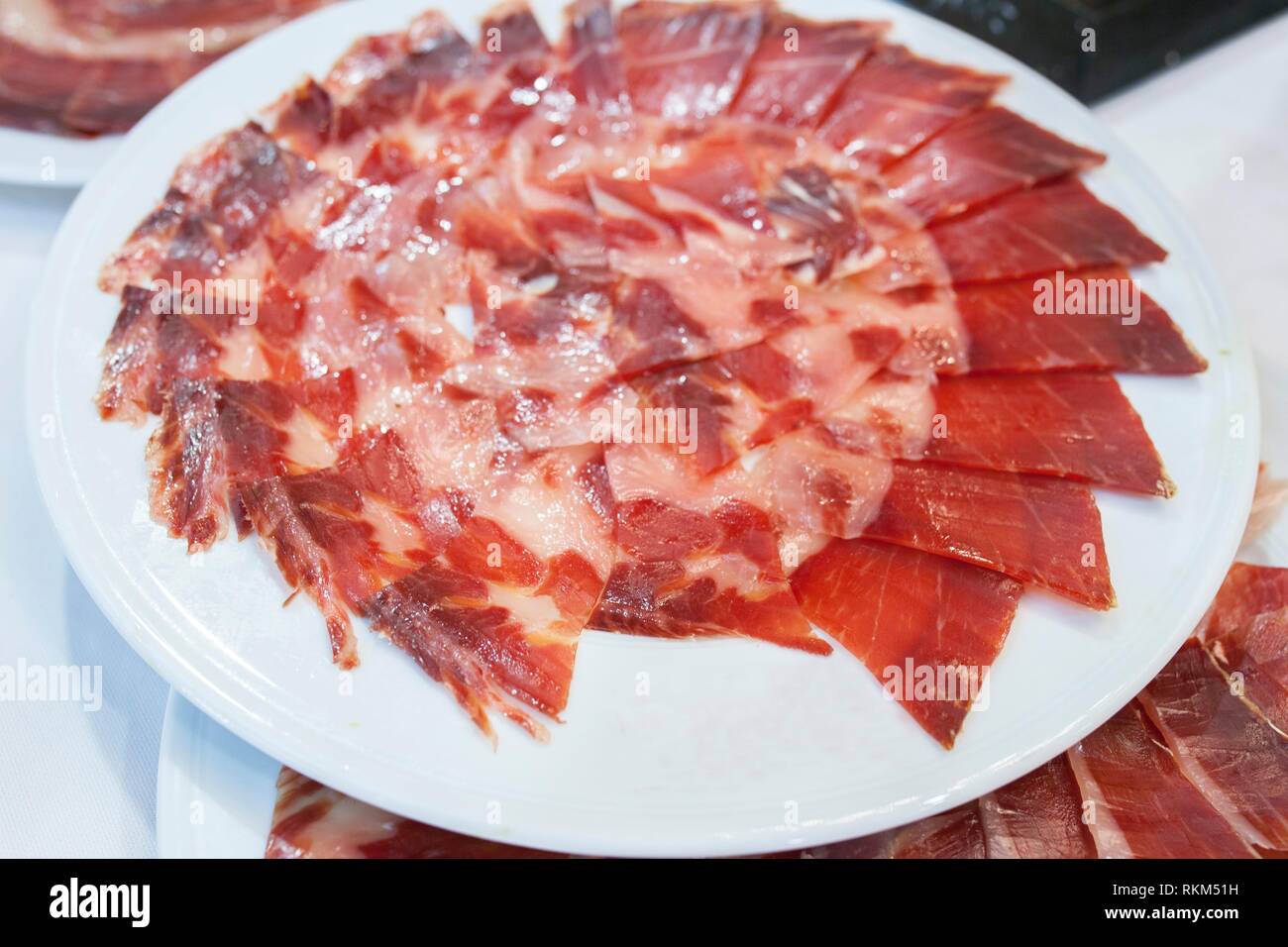 Circular decorative arrangement of iberian cured ham on plate. Empty space on plate to put a brand. Stock Photo