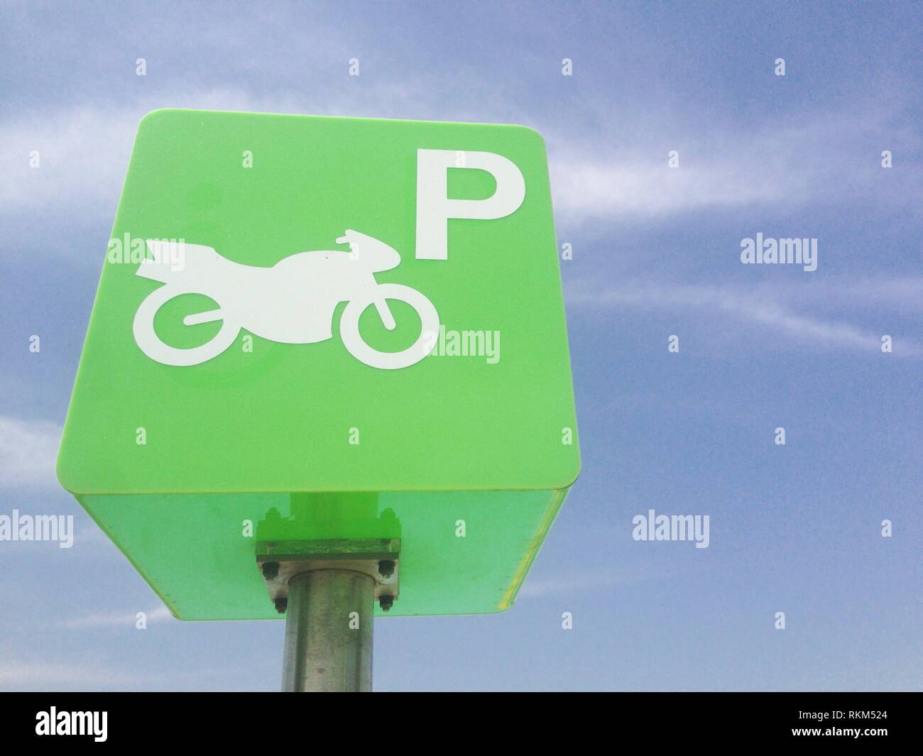Reserved motorcycle park pole green sign against blue sky. Green cube design. Stock Photo