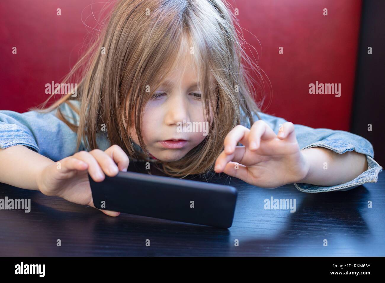 Portrait of five years old child with blue denim jacket, sitting in red