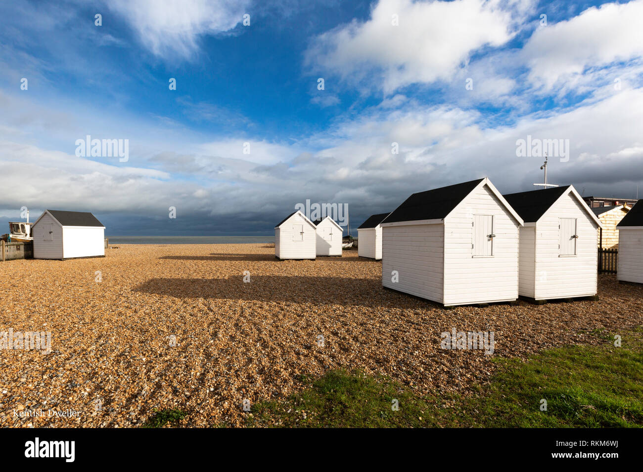 White beach huts during a February afternoon on the shingle beach at Walmer, Deal, Kent, UK. Stock Photo