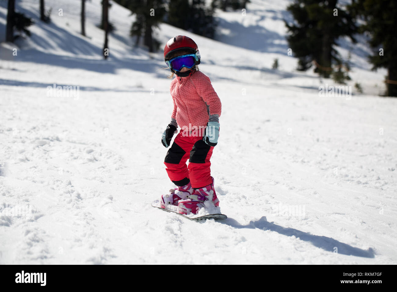 Little Cute 5 Years Old Girl Snowboarding making a Tricks at Ski Resort in Sunny Winter Day. Caucasus Mountains. Mount Hood Meadows Oregon Stock Photo