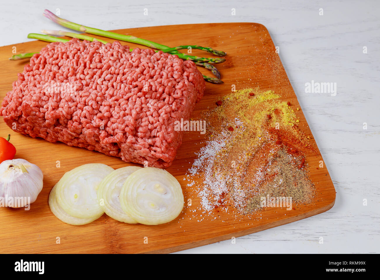 Ground mince beef meat with ingredients for cooking on dark background