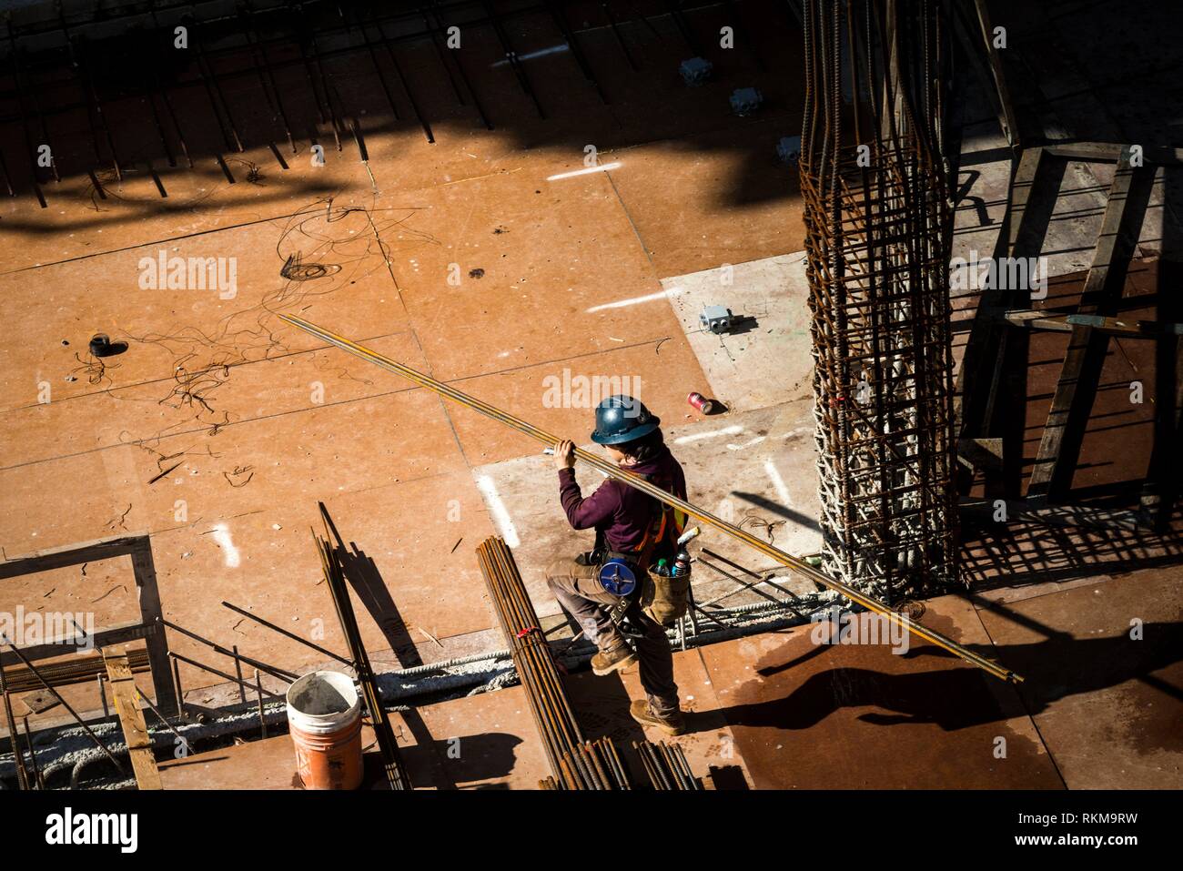 A construction worker carries steel bars at Vancouver House, a tower