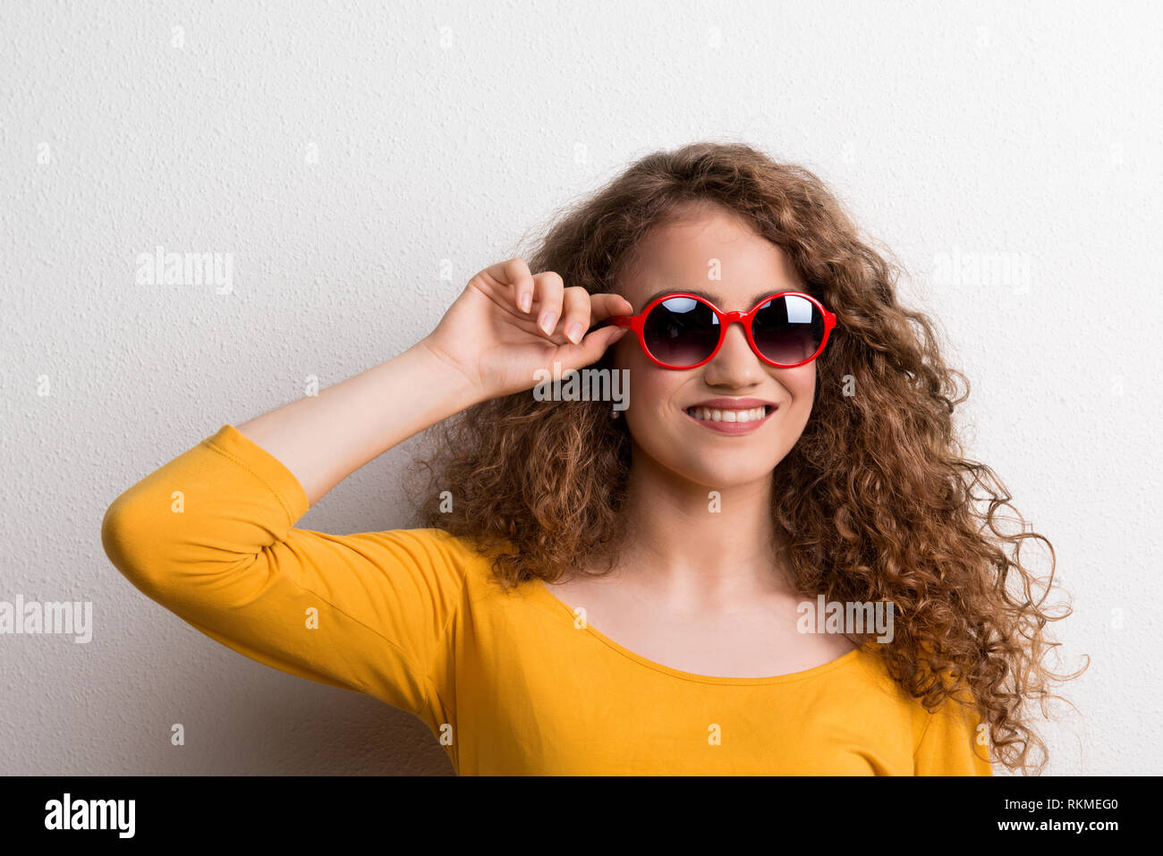 A young beautiful cheerful woman with red sunglasses in studio. Stock Photo