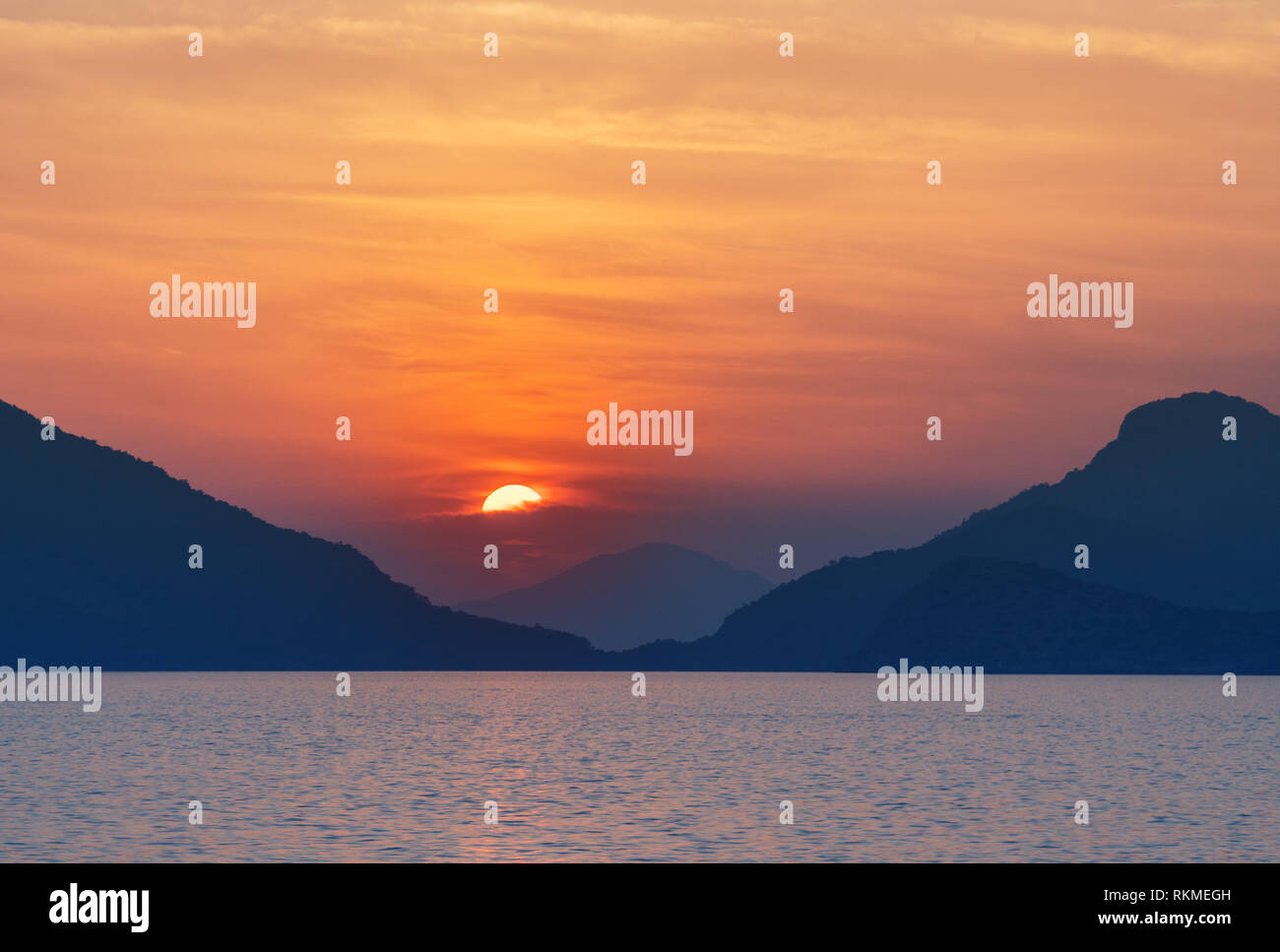 Beautiful sunset at the sea coast. Sun is setting behind the stone and ...