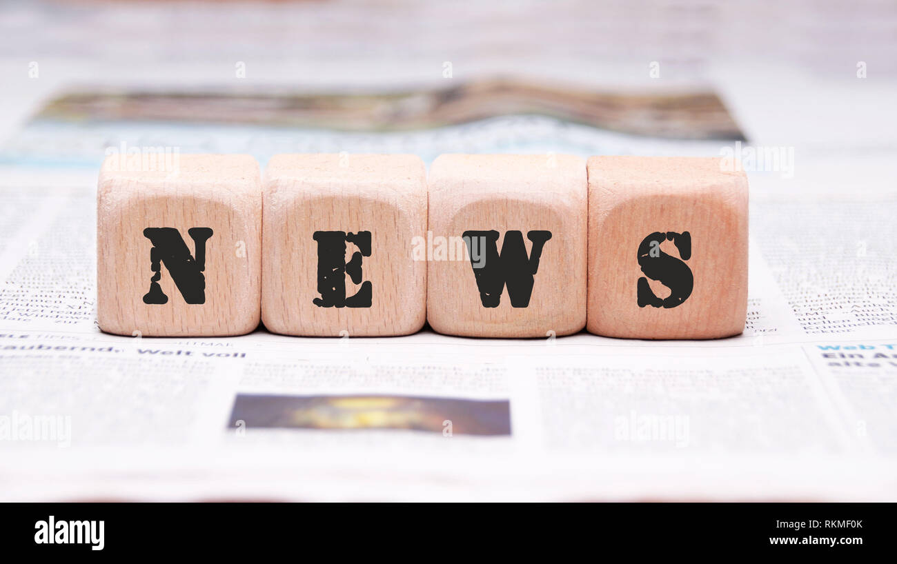 The words News written on wooden cubes placed on a Newspaper Stock Photo
