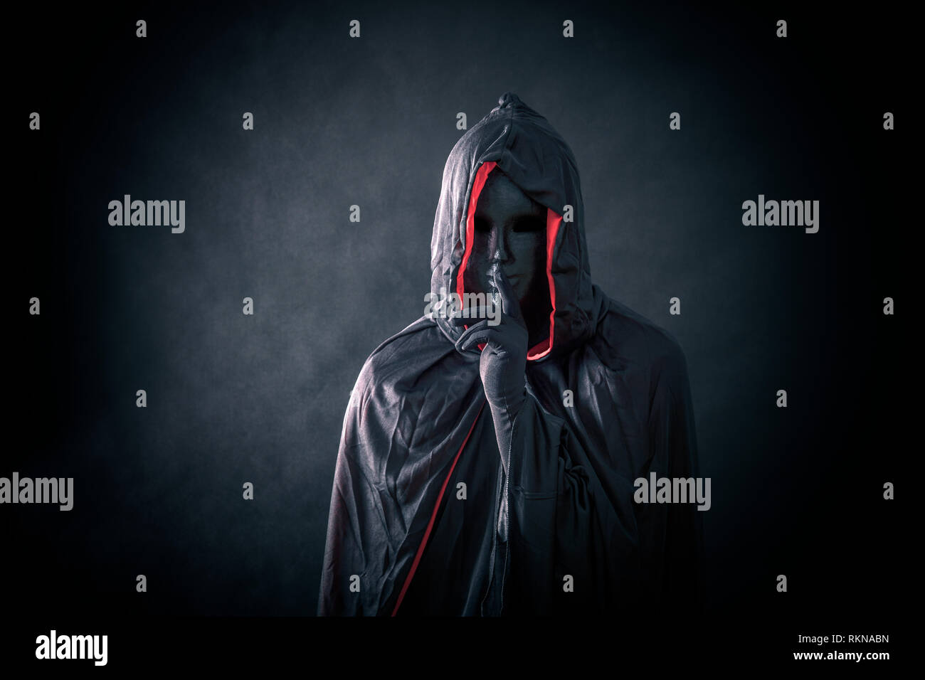 Scary figure with black mask in hooded cloak Stock Photo