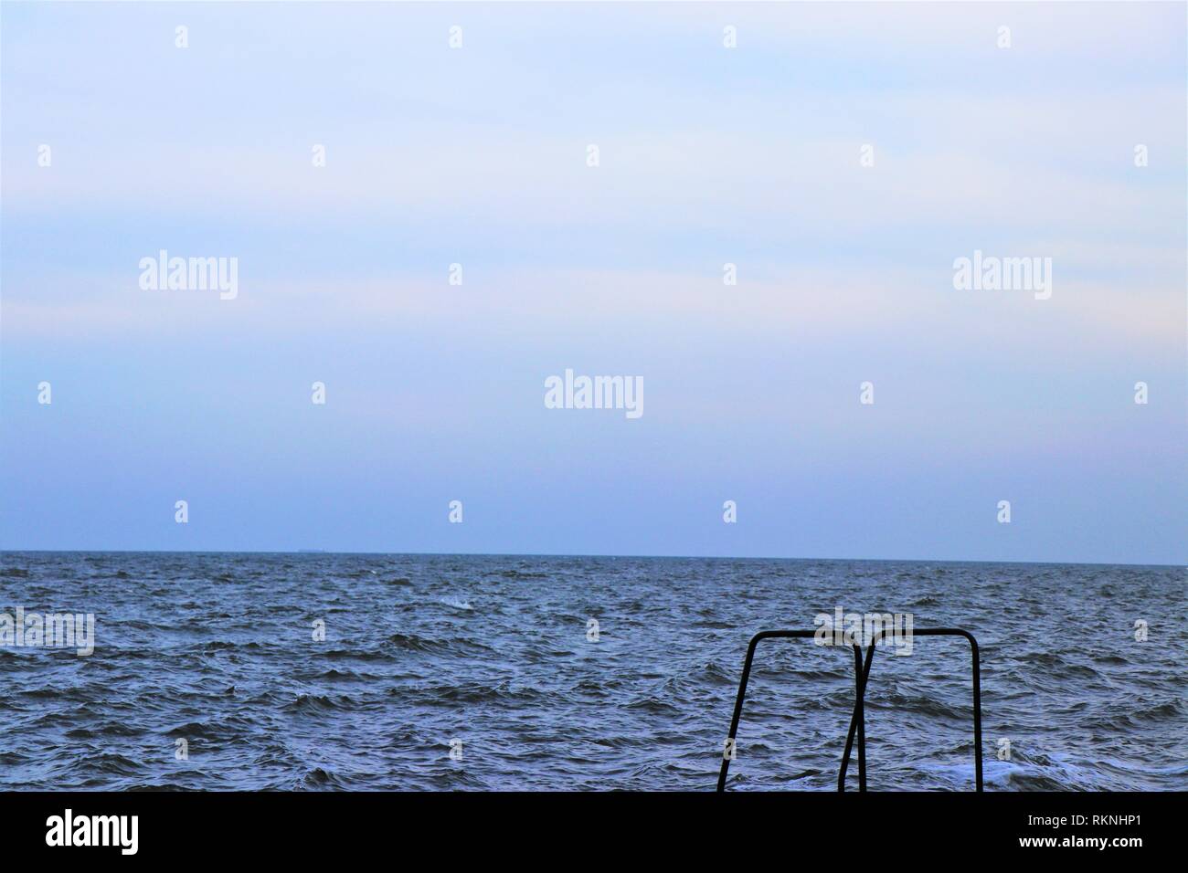 Horizon in the black sea. In the foreground a stepladder. Stock Photo