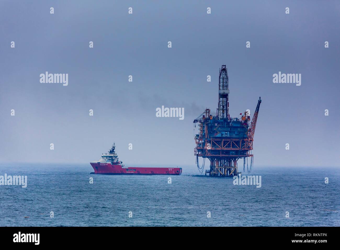 An ocean oil rig and supply ship in the South China Sea near Japan. Stock Photo
