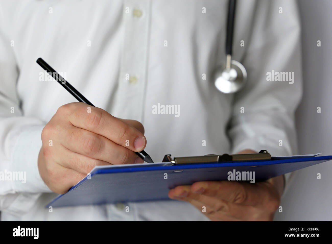 Medical exam, doctor with stethoscope writes a prescription paper. Concept of medicine, diagnosis, filling up an history form and recommend treatment Stock Photo