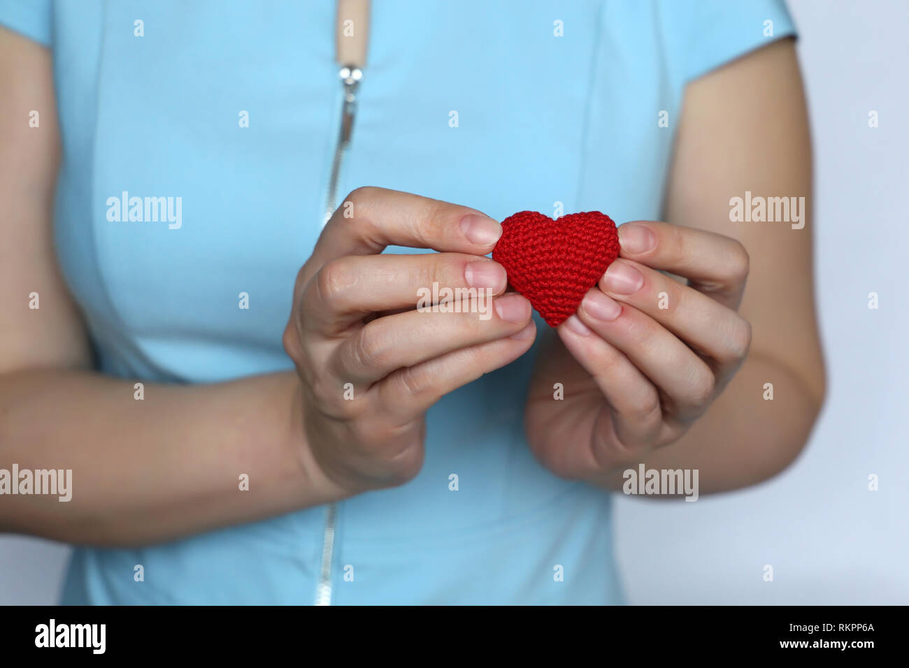 Valentines heart, declaration of love, woman holding red knitted heart on her chest. Concept of romance, charity, saving lives, health care Stock Photo