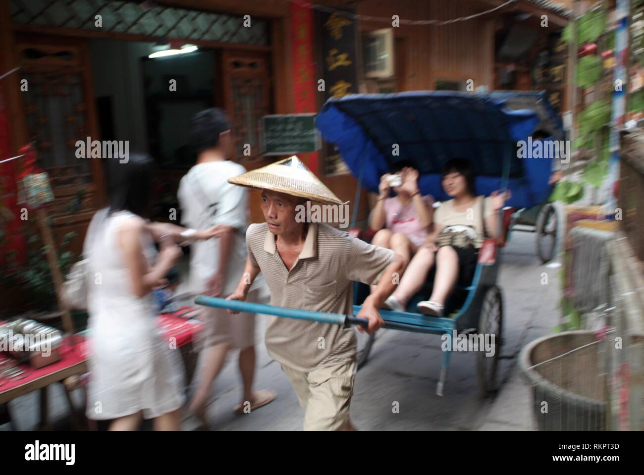 A rickshaw driver pulling tourists through the backstreets of Fenghaung