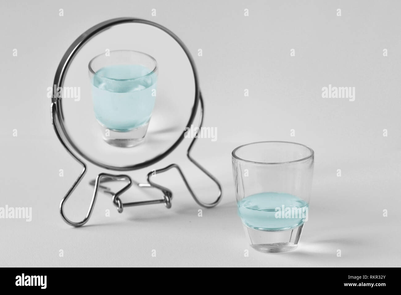 Half-empty water glass looking in the mirror and seeing himself as a full glass - Concept of optimism Stock Photo