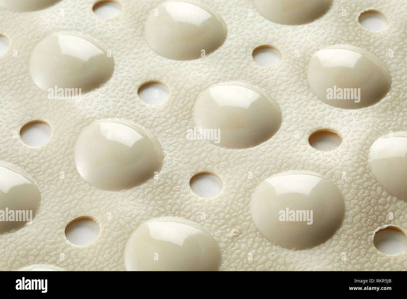 Textured under surface of a rubber bath mat with dimples and holes for