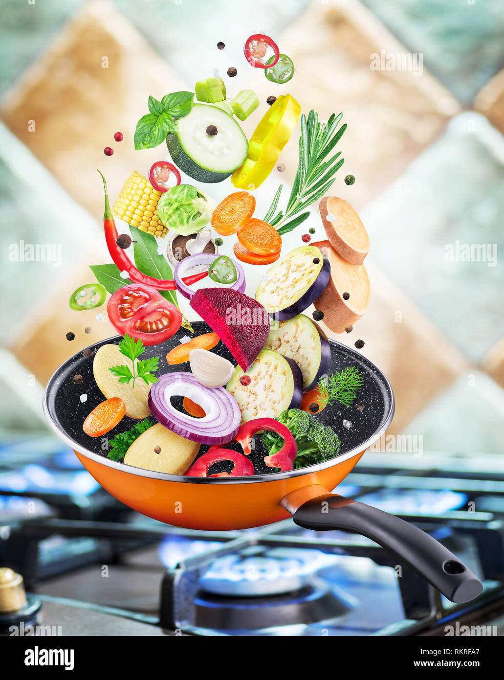 Flying fresh vegetables and spices falling into a pan. Flying motion effect.Gas-stove at the background. Stock Photo