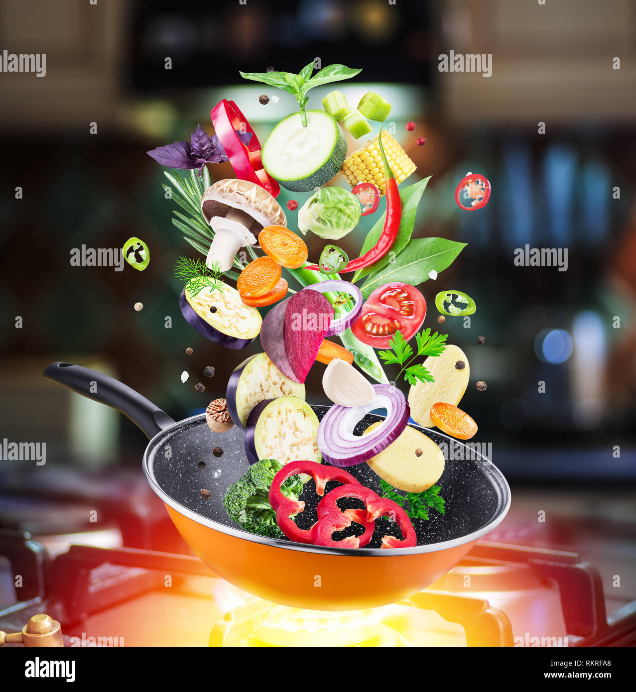 Flying fresh vegetables and spices falling into a pan. Flying motion effect.Gas-stove at the background. Stock Photo