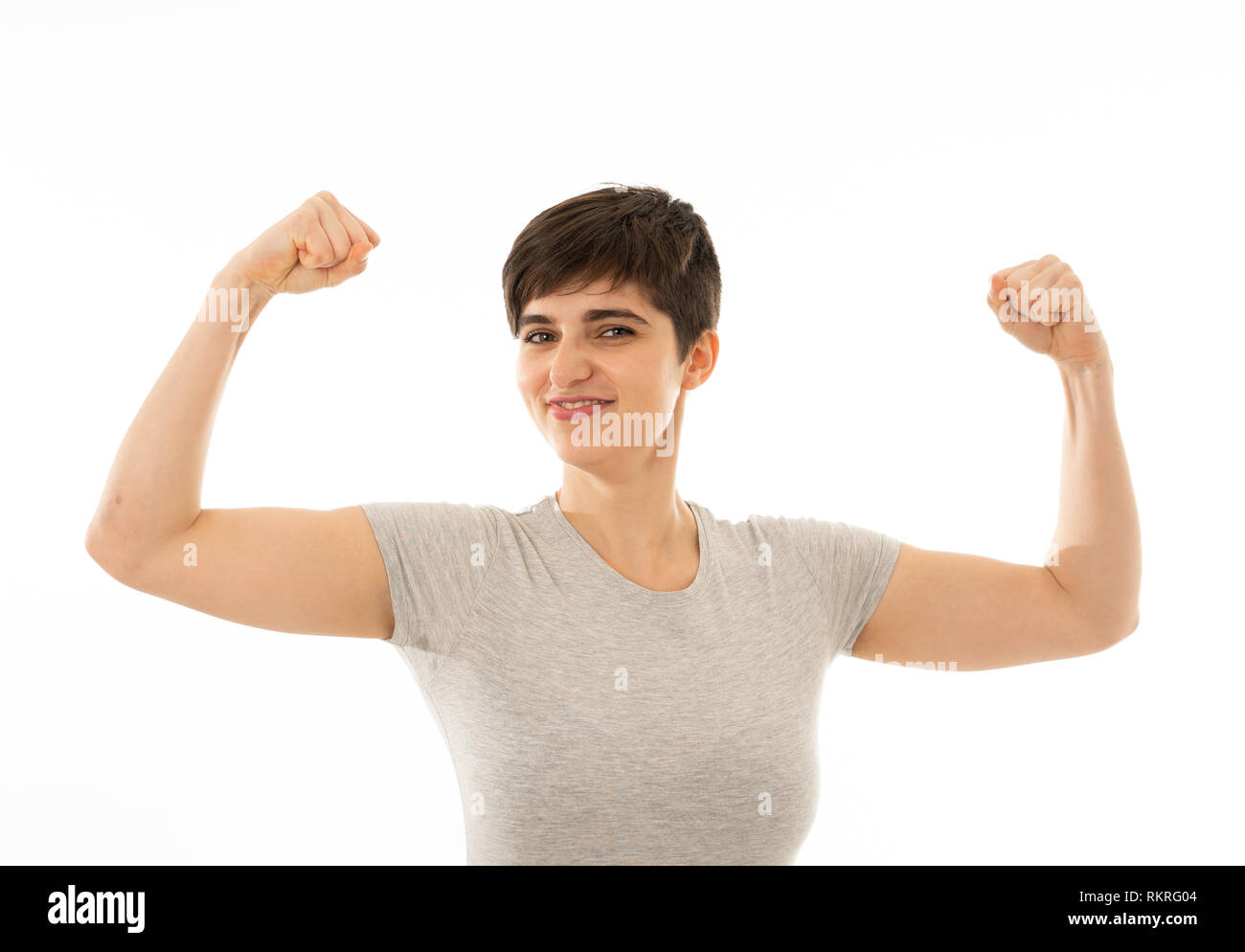 Portrait of young strong beautiful and funny caucasian woman showing arms muscles smiling proud having fun. In people, Happiness, Fitness, success Hum Stock Photo