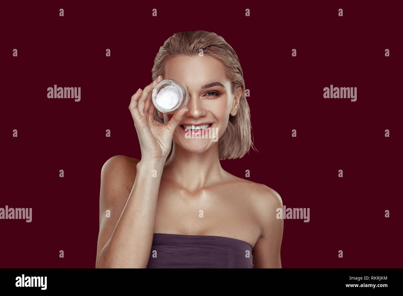 Young model smiling while promoting her favorite cream Stock Photo