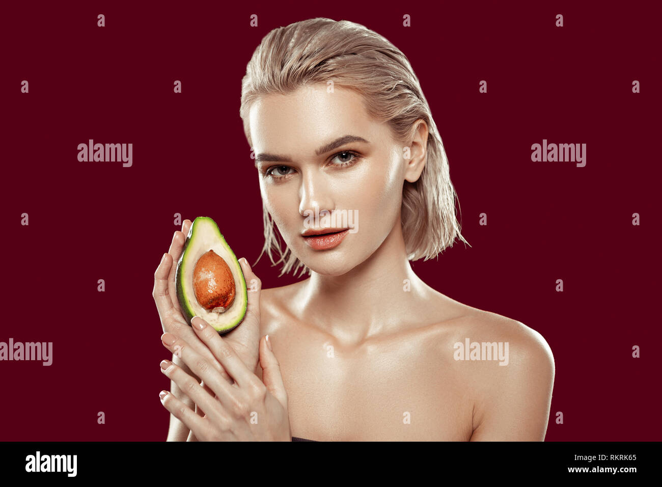 Young appealing photo model posing with avocado in her hand Stock Photo