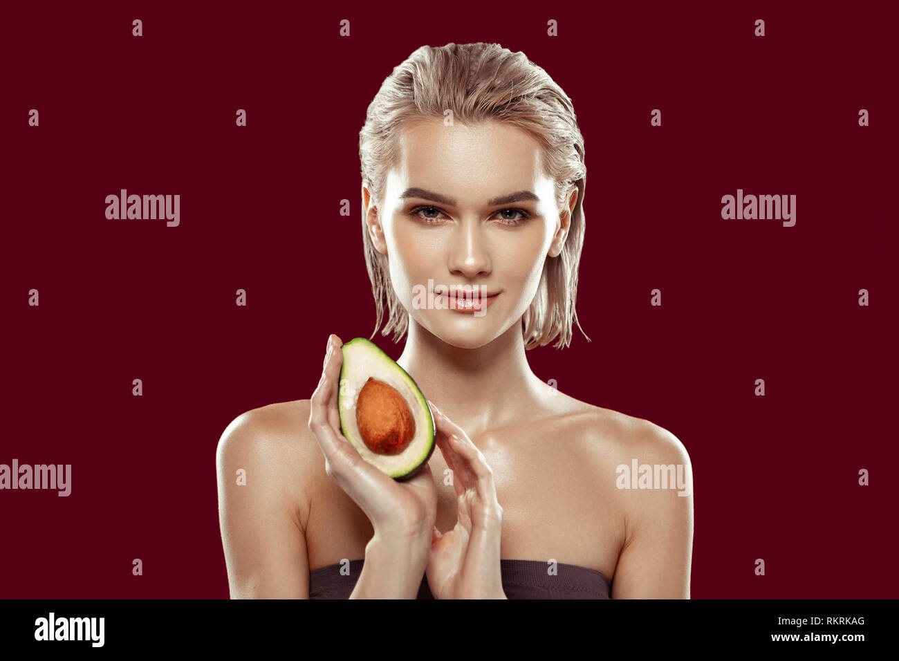 Model with bob cut having nice makeup while posing with avocado Stock Photo
