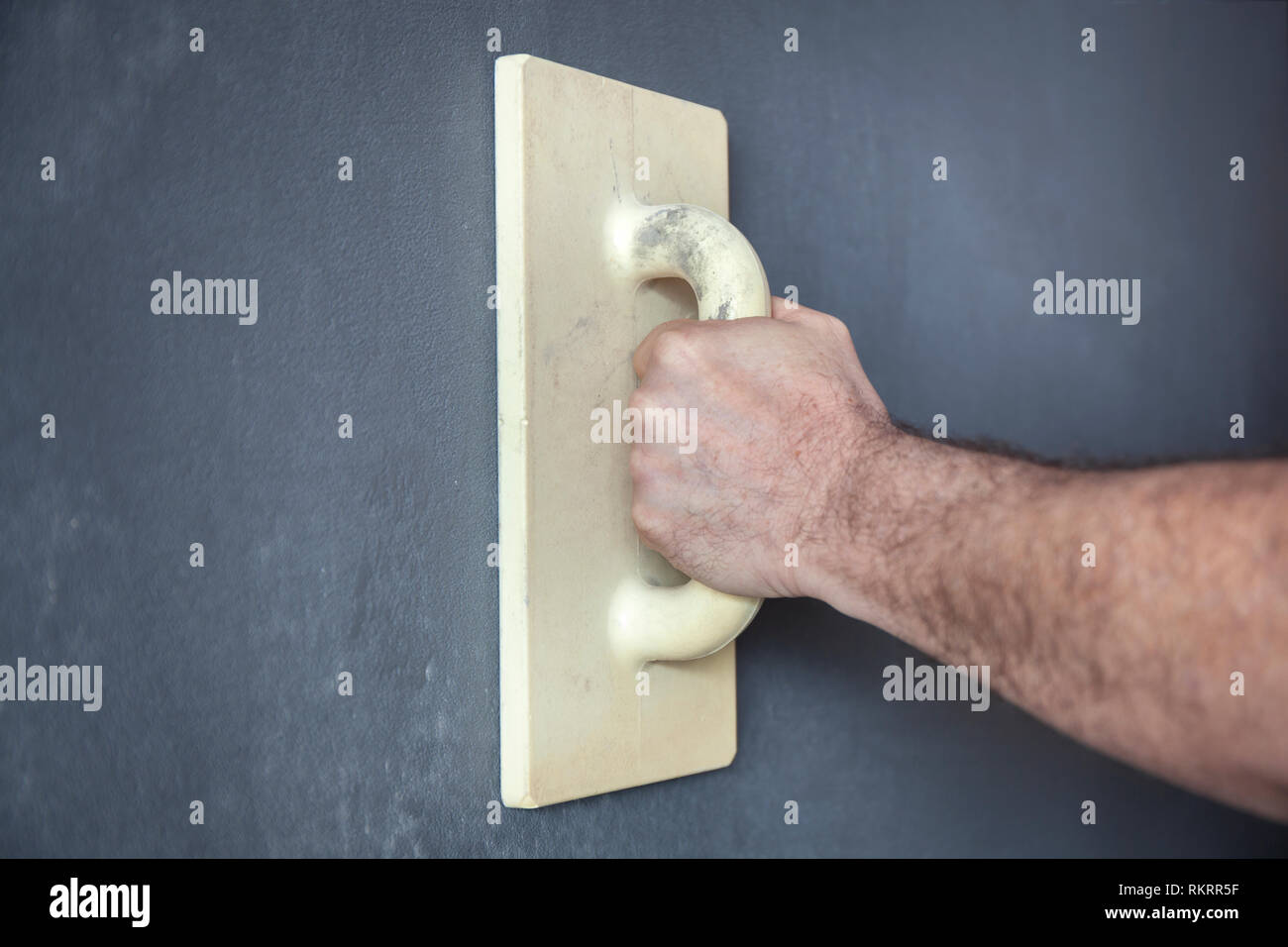 Workers hand with a trowel smoothing a wall with decorative plaster Stock Photo