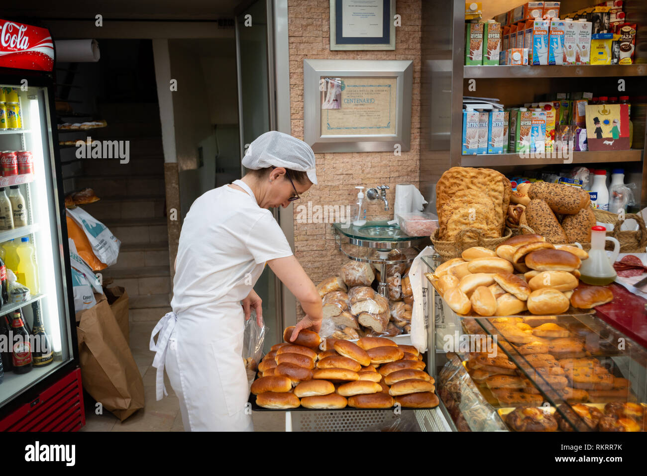 A member of staff sorts freshly baked bread in a patisserie, cake shop