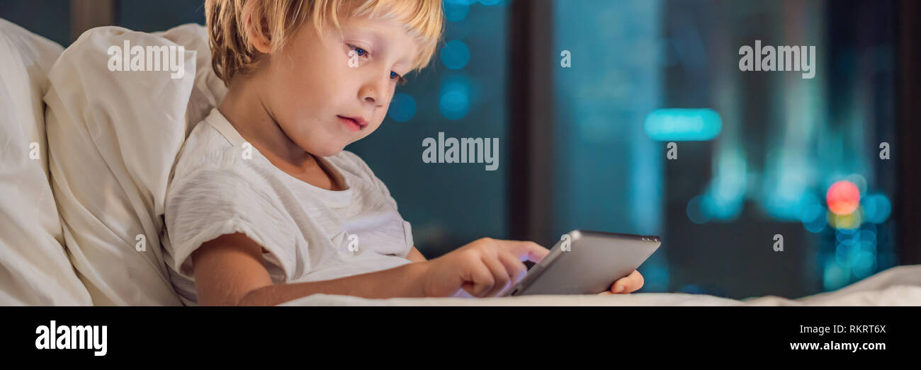 The boy uses the tablet in his bed before going to sleep on a