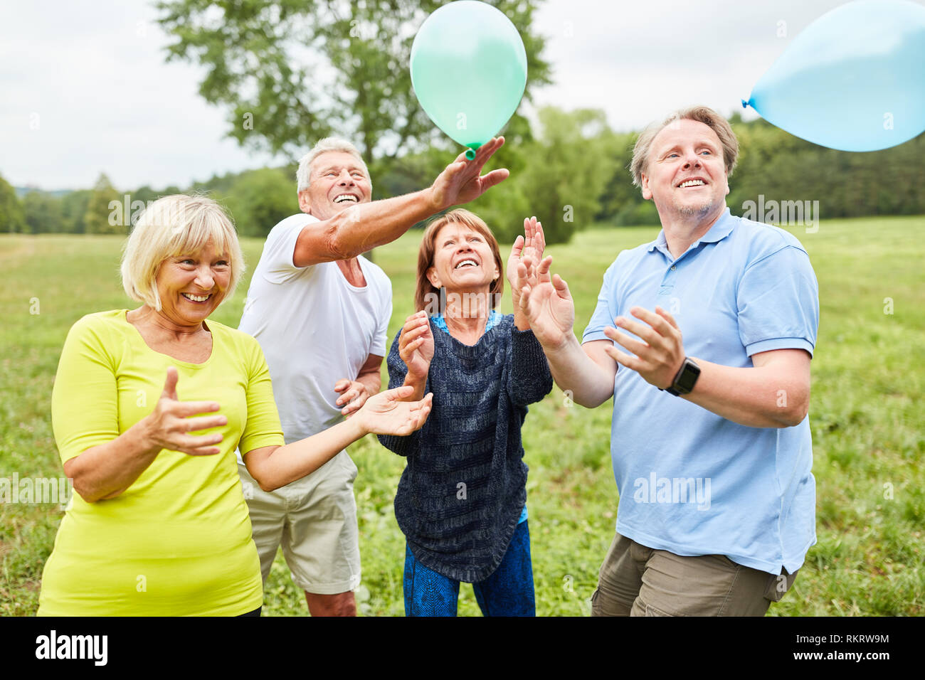 Cheerful seniors playing with balloons a party game in the garden in summer Stock Photo