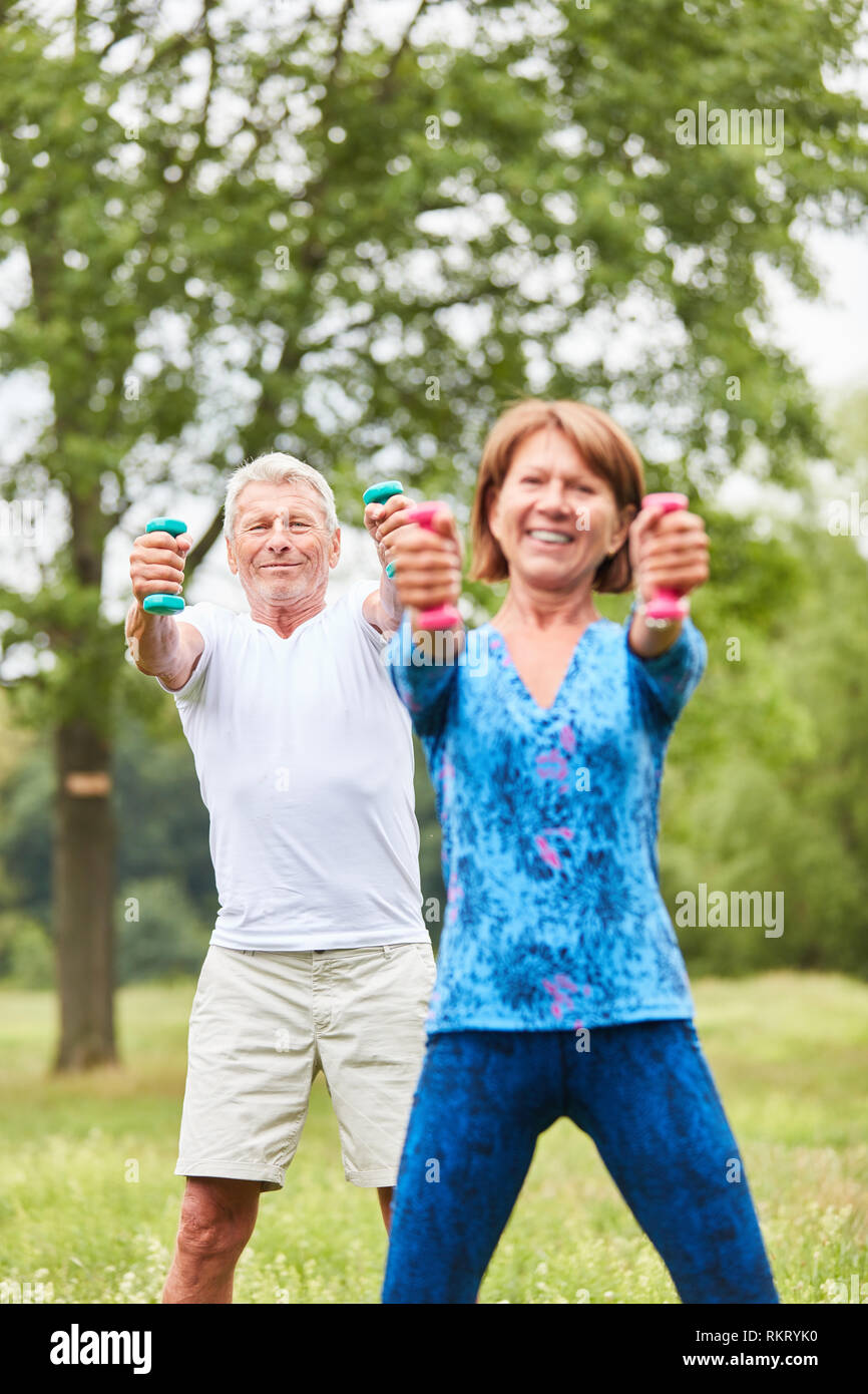 Athletic senior couple doing strength training with dumbbells in rehab Stock Photo