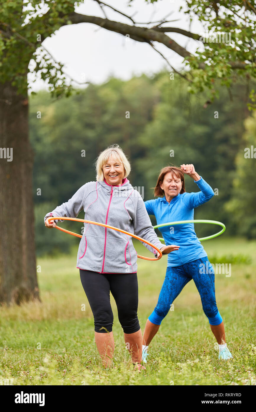 Two women doing senior sports in the park train their fitness with the tire Stock Photo