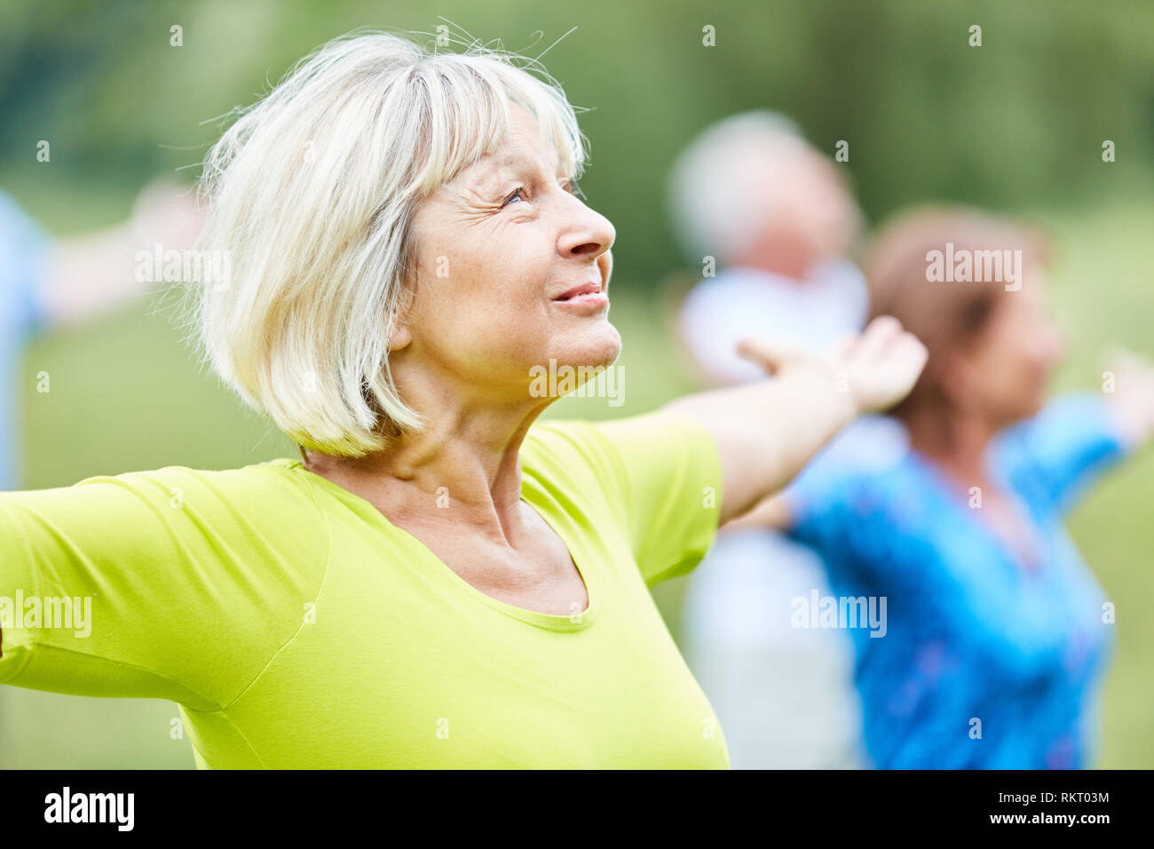 Active seniors in a yoga class do a breathing exercise for relaxation Stock Photo