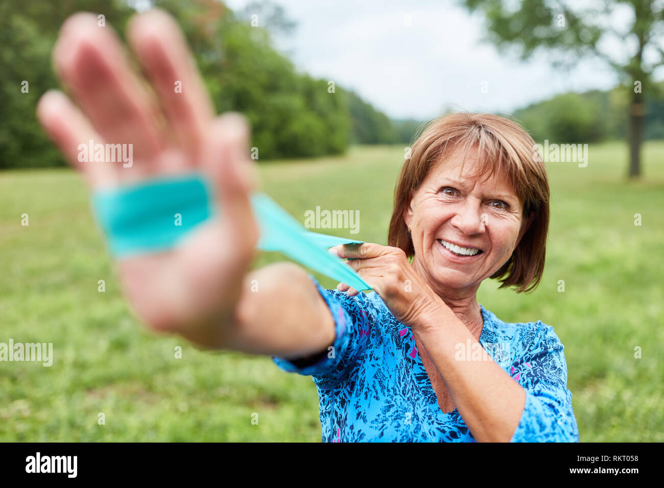 Vital senior woman doing physiotherapy with the stretch band in the rehab Stock Photo