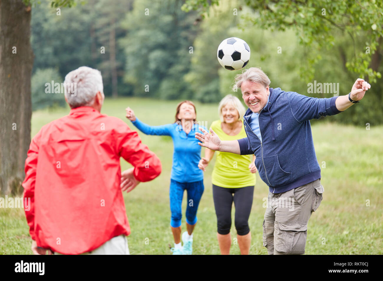 Senior man playing header in a soccer game together with friends Stock Photo