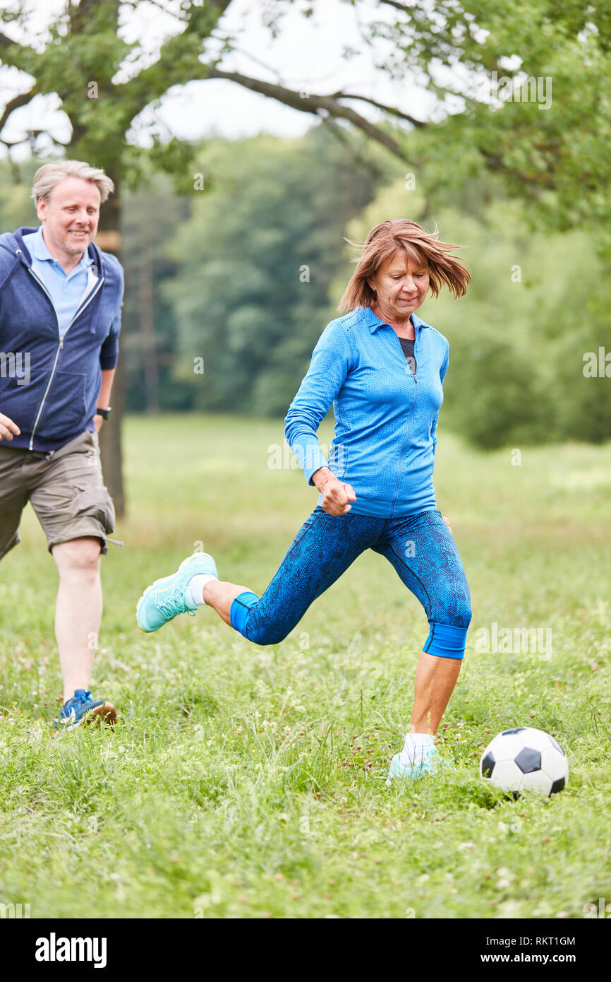 Senior woman playing football with friends in the park as a senior