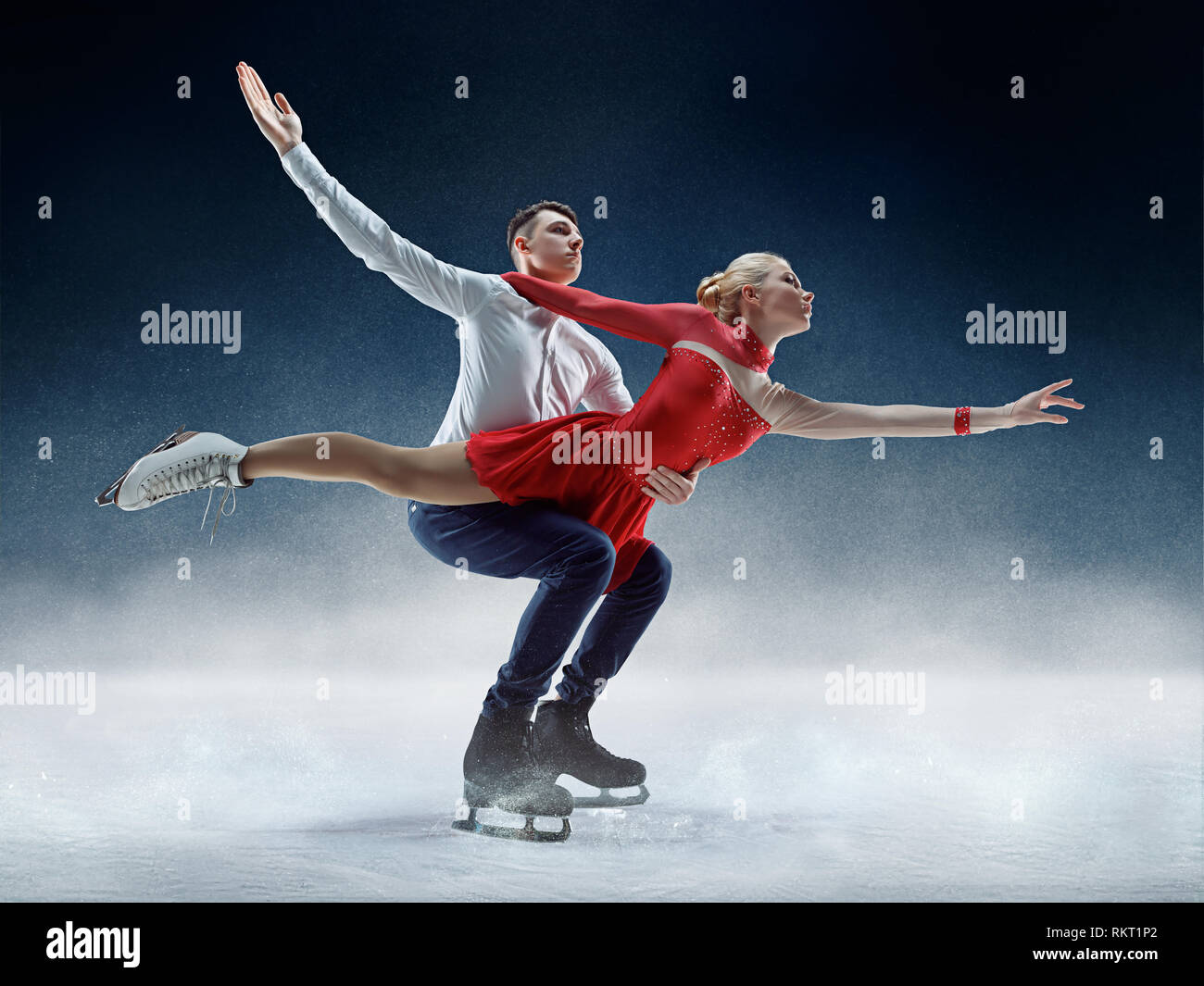 Professional man and woman figure skaters performing show or competition on ice arena Stock Photo