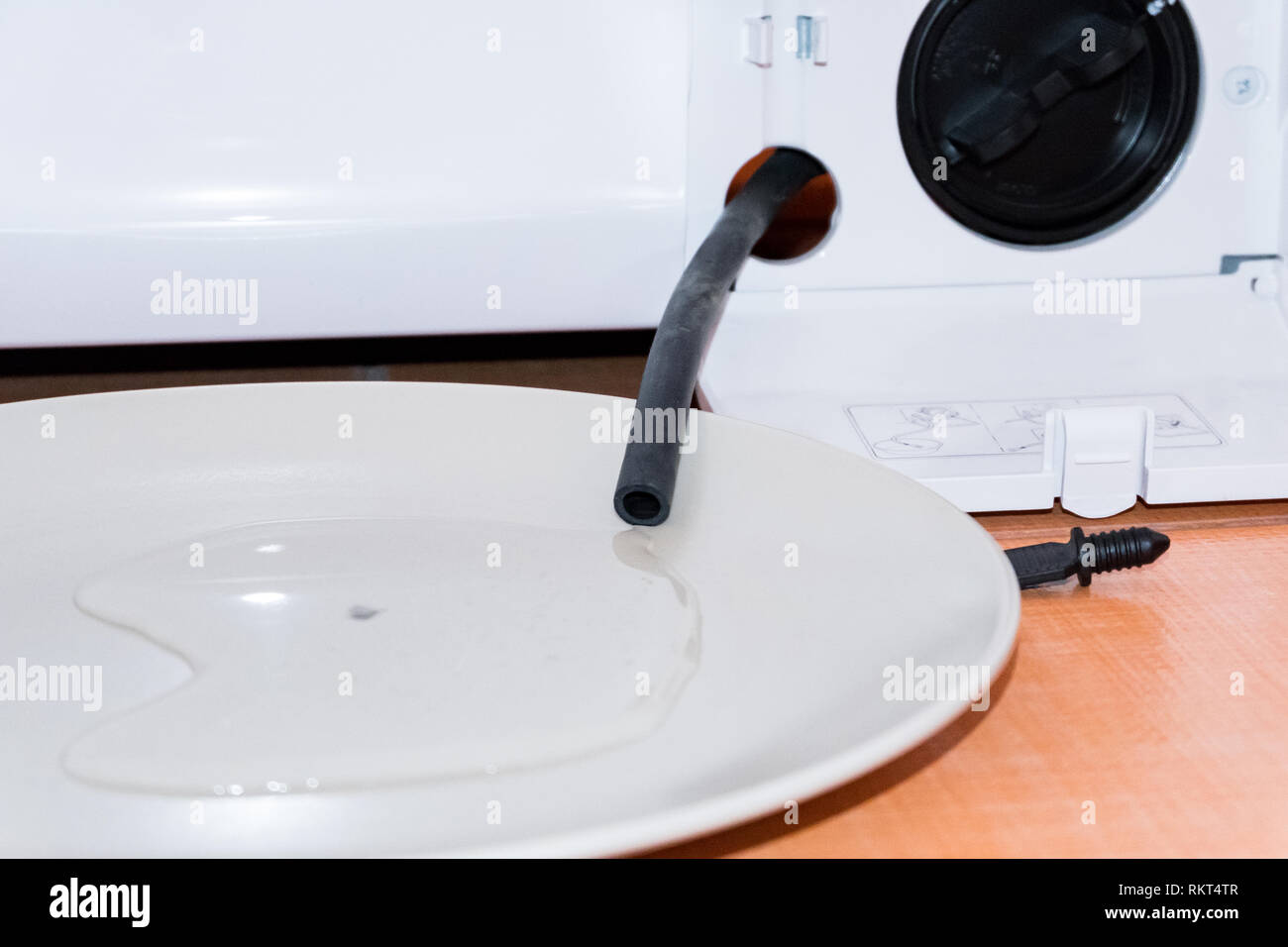 Cleaning the washing machine filter. Draining water from a black tube