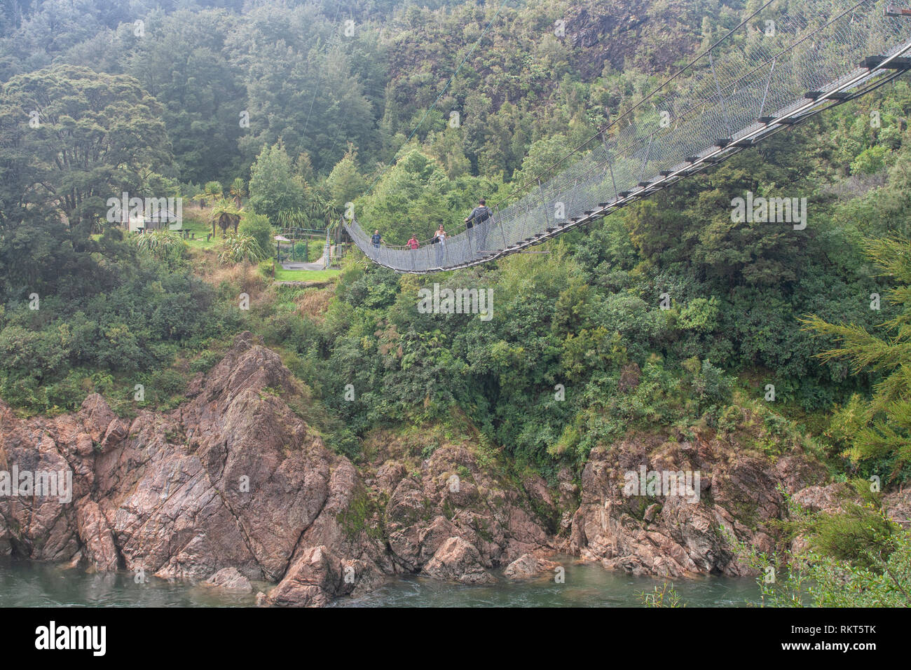 People on a large suspension bridge above river in New Zealand Stock Photo