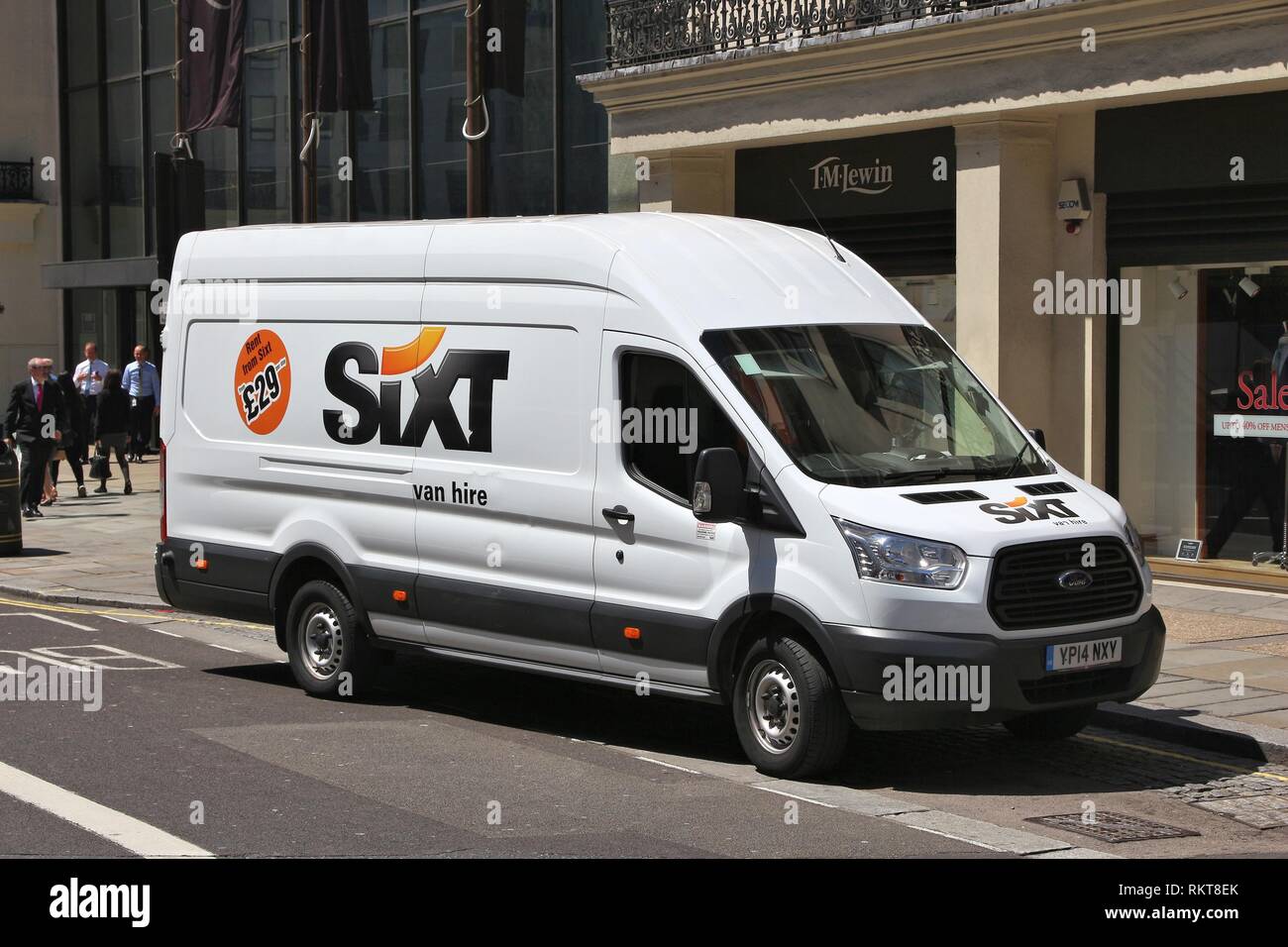 People walk by a Sixt van for hire 