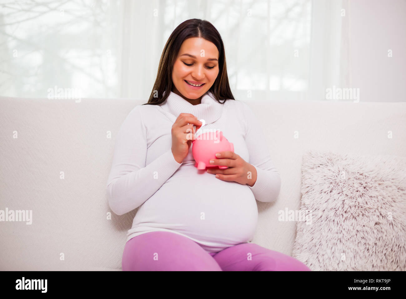 Happy pregnant woman saving money for her child. Stock Photo