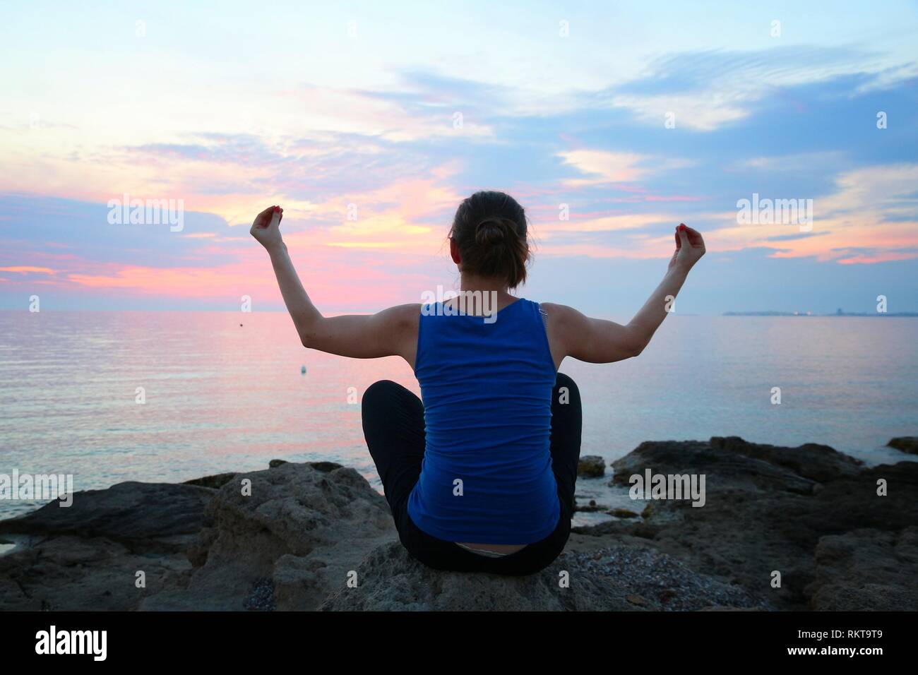 Yoga asana - tranquil meditation exercise with sunset view of Italian coast. Sukhasana - decent pose. Stock Photo