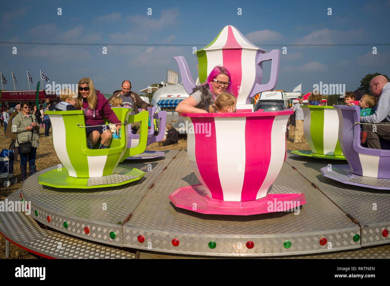 Families enjoying a ride on a teacup fairground roundabout at an agricutural show near Henley-on-Thames, Oxfrdshire. Stock Photo