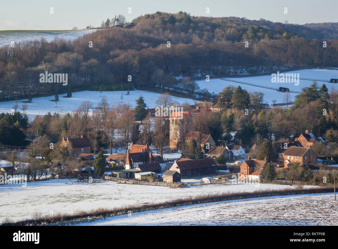 A winter view over the Chiltern village of Fingest with snow on the ground and Cobstone Windmill  on the hill above. Stock Photo