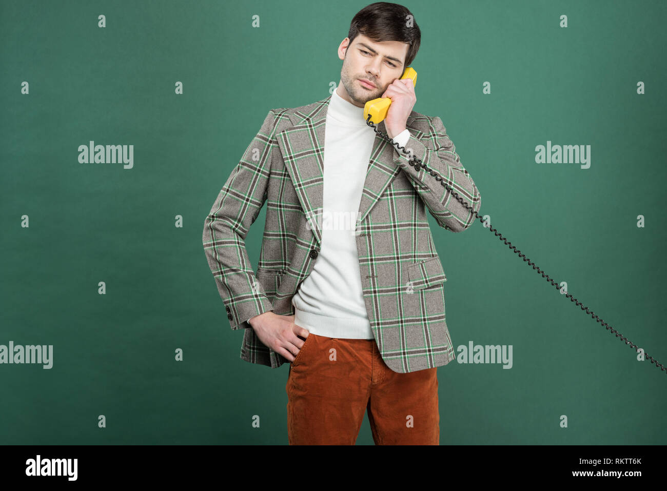 handsome man in vintage clothes talking on retro telephone isolated on green Stock Photo