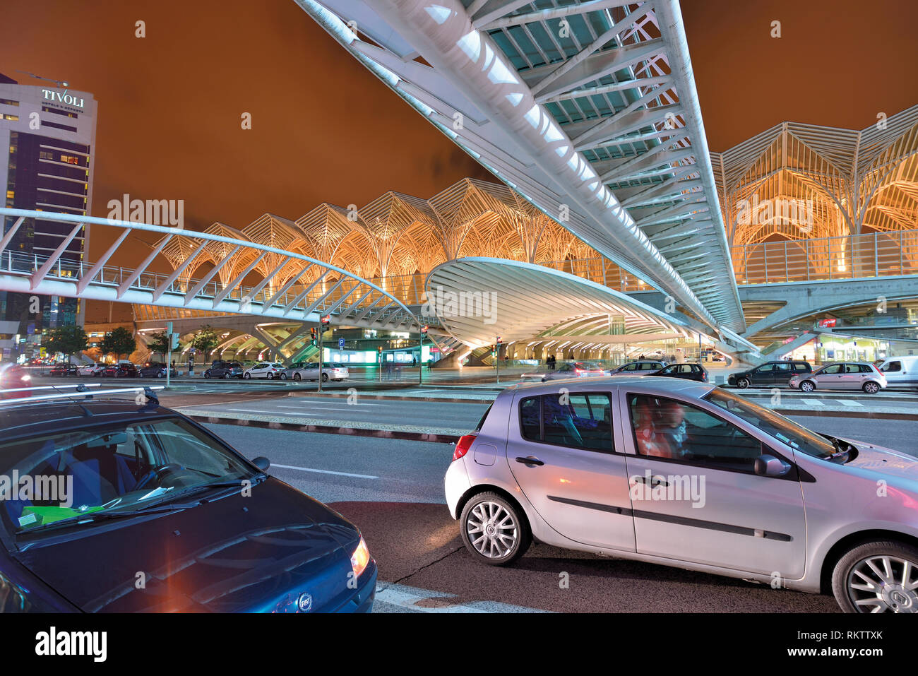 Evening traffic in large road with futuristic steel roof and bridge Stock Photo