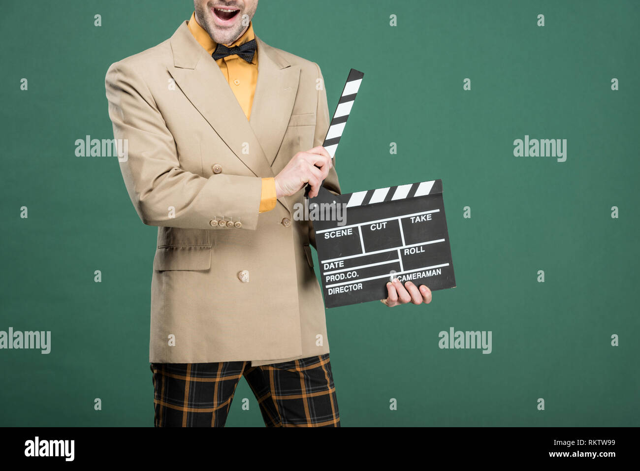 cropped view of excited man in vintage clothes holding film clapperboard isolated on green Stock Photo